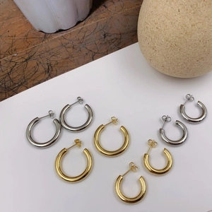 Detailed close-up of gold and silver C-shaped metal hoop earrings in varied sizes