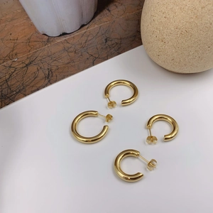 Minimalist chunky golden hoop earrings with high-polish finish on a clean aesthetic background