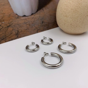 Polished silver C-shaped hoop earrings set in two sizes on a minimalist background