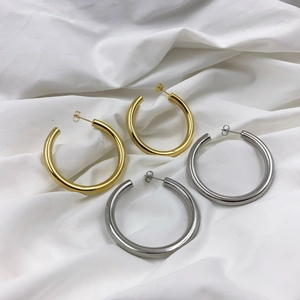 Flat lay of large chunky C-shaped hoop earrings in polished gold and silver metallic finishes