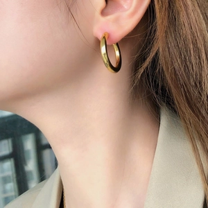 Close-up of polished gold C-shape hoop earrings worn by a model for a vintage look