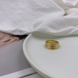 Polished triple layered gold titanium steel ring displayed on a white ceramic tray