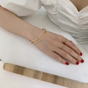 Elegant gold double-layered bangle and minimalist rings set for women on white background