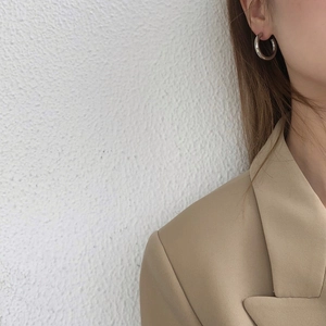 Close-up of thick silver C-shaped hoop earring on model with minimalist modern style