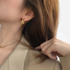 Detail of gold C-shaped hoop earrings and ball pendant necklace set on model