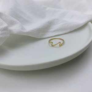 Close-up of a minimalist 18k gold plated stainless steel ring with wave pattern