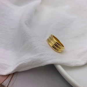 Detailed view of layered gold-plated titanium ring with spiral design on white fabric