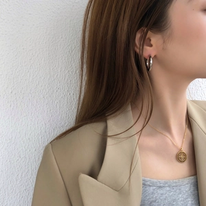 Close-up of a model wearing a gold starburst necklace and classic silver hoop earrings