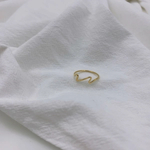 Close-up of minimalist 18k gold plated titanium steel wavy ring on white linen texture