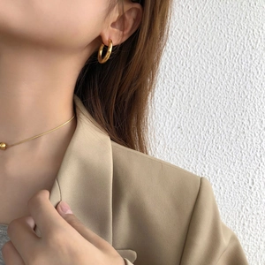 Close-up of elegant gold thick hoop earrings paired with a beige blazer for office style