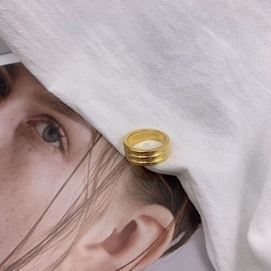 Macro detail of triple-layer gold titanium steel ring resting on textured linen fabric