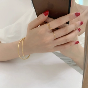 Minimalist gold double-layered bracelets and rings set styled on model hands