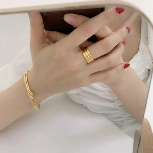 Detail of minimalist gold layered ring and knot cuff bracelet worn by a model
