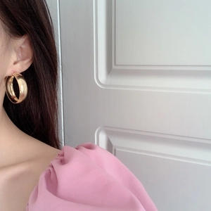 Boucles d'oreilles créoles dorées géométriques surdimensionnées portées par un mannequin