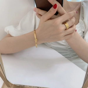 Detail of minimalist triple-layered gold-plated ring and knotted bangle on a model
