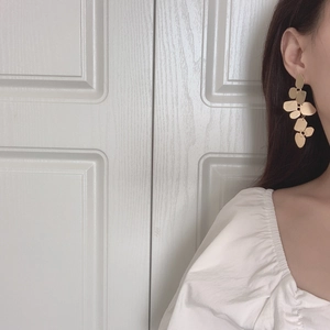 Detail of elegant gold leaf-shaped dangle earrings on model with multi-layered design