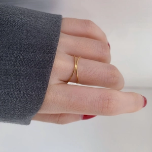 Detail of a minimalist gold crisscross ring shown on a hand with a modern X-shaped design