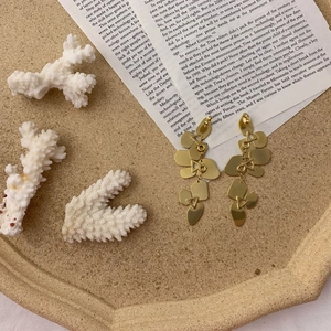 Detailed view of gold geometric drop earrings with heart and triangle dangling shapes