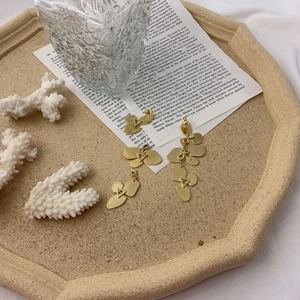 Minimalist gold geometric layered petal earrings set displayed on vintage sand tray