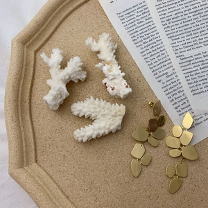 Detail of matte gold irregular geometric earrings on beige textured display tray