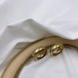 Boucles d'oreilles créoles dorées géométriques en C sur présentoir élégant