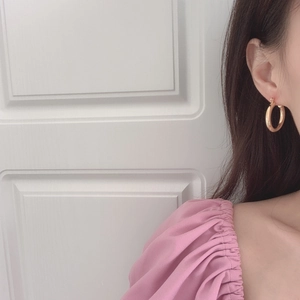 Close-up of a model wearing minimalist thick gold hoop earrings with a polished finish
