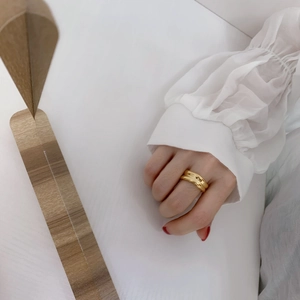 Detail of wide gold wrap ring with natural textured surface worn on a model's finger