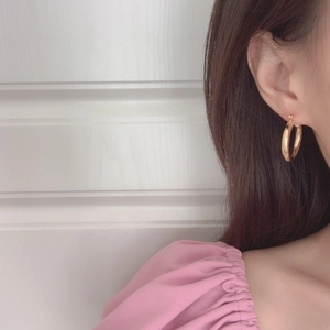 Close-up of polished gold hoop earrings worn by a model for a minimalist fashion look