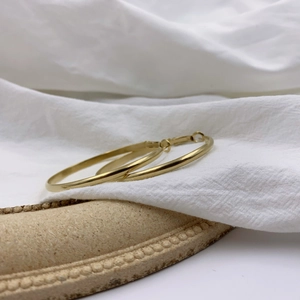 Boucles d'oreilles créoles dorées épaisses pour femmes sur fond de tissu texturé