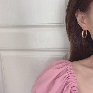 Detailed view of chunky 18K gold hoop earrings with polished finish on a model