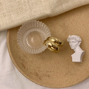 Détail de boucles d'oreilles créoles dorées épaisses avec finition métal poli