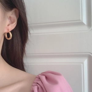Close-up of chunky gold hoop earrings with a polished metallic finish worn on ear