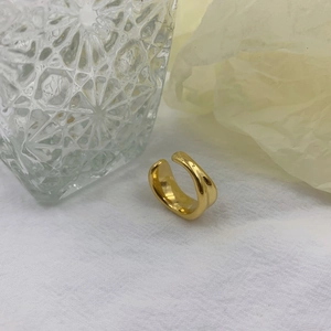 Macro detail of irregular gold wave ring with polished finish on a textured background