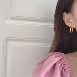 Close-up of polished gold hoop earrings on model showing size and metallic finish