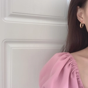 Minimalist golden hoop earrings with high-polish finish worn by a model in a casual setting