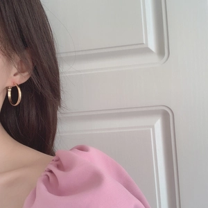 Gros plan d'élégantes créoles épaisses dorées portées par un mannequin en rose