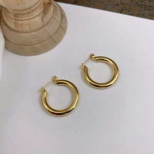 Close-up of chunky gold hoop earrings with a polished mirror finish and clip closure