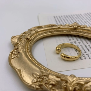 Détail d'une bague ouverte dorée de style vintage sur un cadre ancien et un livre