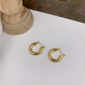 Macro detail of polished chunky gold hoop earrings with secure latch-back closure