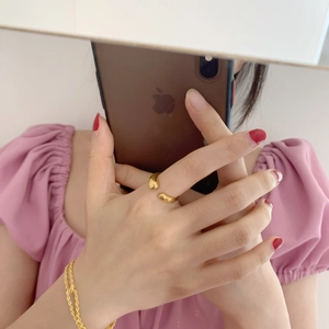 Détail d'une bague ouverte dorée et d'un bracelet torsadé portés par un mannequin