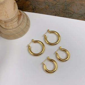 Close-up of chunky gold hoop earrings in two sizes with a high-polished metallic finish