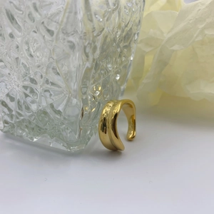 Macro shot of an irregular gold wide ring featuring a unique crushed fluid metal texture