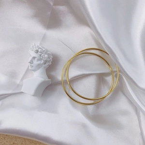 Detailed view of dual gold minimalist bangles on elegant white silk with David bust