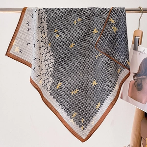 Close-up of geometric letter print silk scarf with brown border detail