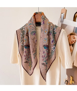 Detail of vintage floral and butterfly print scarf styled on a beige sweater