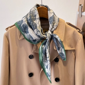 Foulard quadrato con stampa di rose grigie e bordi verde scuro su un elegante trench coat
