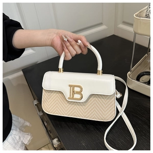 Dettaglio borsa in pelle bianca e paglia con fibbia logo B dorata e manico tondo