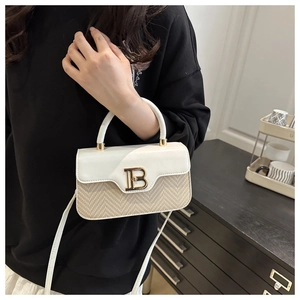 Dettaglio di una borsa intrecciata bicolore con patta in pelle e fibbia dorata a B