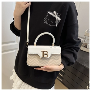 Dettaglio della borsa a tracolla in paglia intrecciata con logo B d'oro e pelle