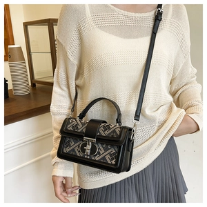 Detail of jacquard geometric pattern handbag with leather trim and metal clasp closure